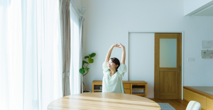 女性　リビング　背伸び